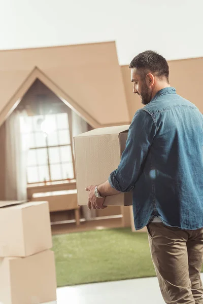 Man with boxes moving into new cardboard house — Stock Photo
