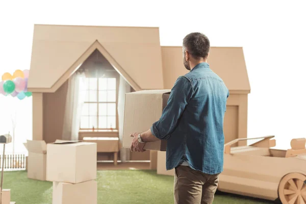 Hombre con cajas moviéndose en nueva casa de cartón aislado en blanco - foto de stock