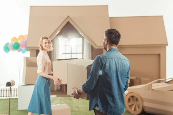 Feliz pareja moviéndose en nueva casa de cartón - foto de stock