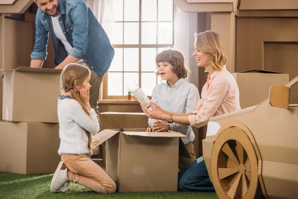 Молода сім'я розпаковує коробки під час переїзду в новий картонний будинок — стокове фото