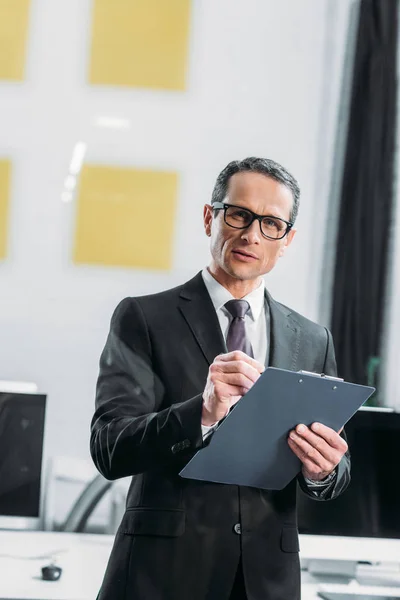 Retrato de empresario enfocado con bloc de notas en la oficina - foto de stock