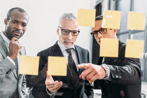 Empresários multiculturais olhando para notas durante reunião no escritório — Fotografia de Stock