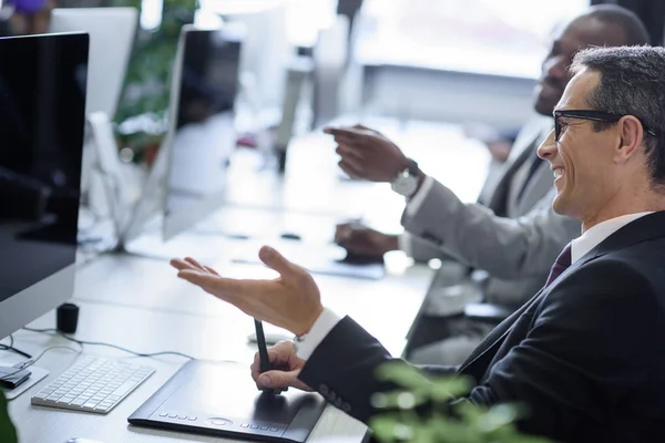 Focalizzazione selettiva di uomini d'affari multiculturali che conversano sul posto di lavoro in ufficio — Foto stock