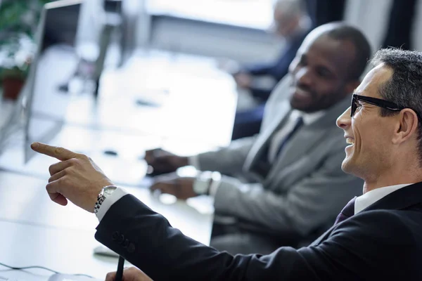 Enfoque selectivo de los hombres de negocios multiculturales que tienen conversación en el lugar de trabajo en la oficina - foto de stock