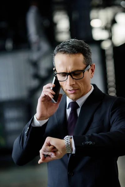 Портрет бизнесмена, проверяющего время во время разговора на смартфоне — стоковое фото