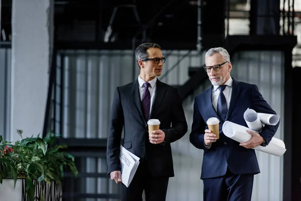 Retrato de hombres de negocios con café para ir en manos caminando en la oficina - foto de stock