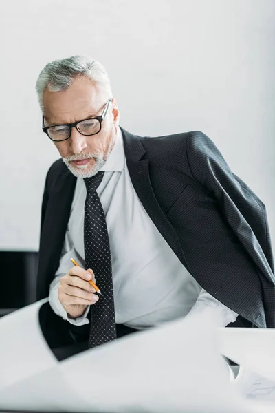 Retrato de arquiteto focado trabalhando com plantas no escritório — Fotografia de Stock