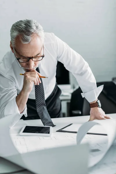 Porträt eines konzentrierten Architekten, der mit Entwürfen im Büro arbeitet — Stockfoto