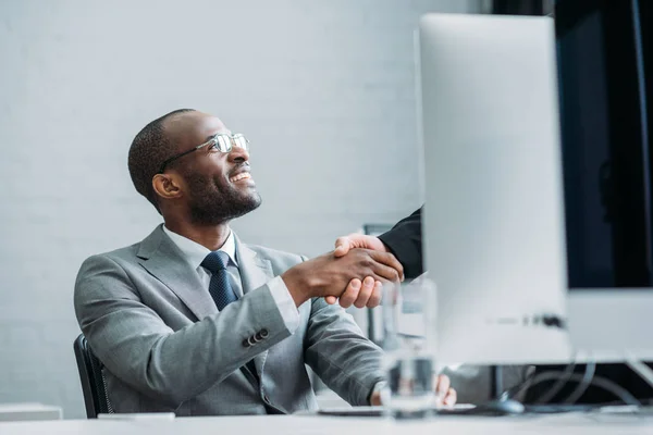 Vue partielle de l'homme d'affaires afro-américain et collègue serrant la main sur le lieu de travail — Photo de stock