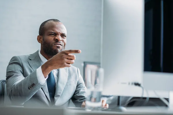 Portrait of african american businessman pointing at computer screen at workplace — Stock Photo