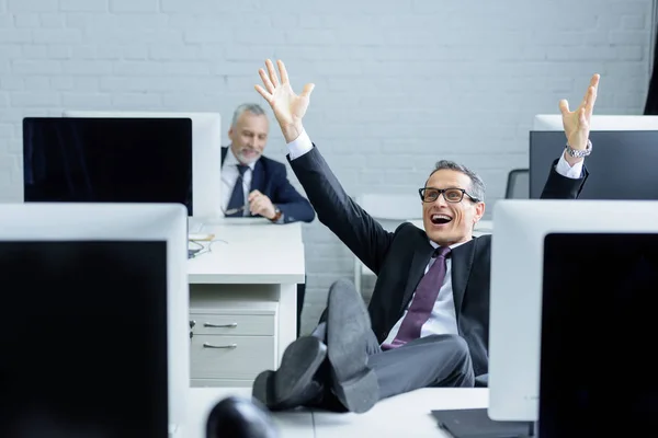 Foyer sélectif de l'homme d'affaires heureux assis sur le lieu de travail avec les jambes sur la table — Photo de stock