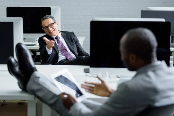 Вибірковий фокус мультикультурних бізнесменів, які розмовляють на робочому місці в офісі — стокове фото