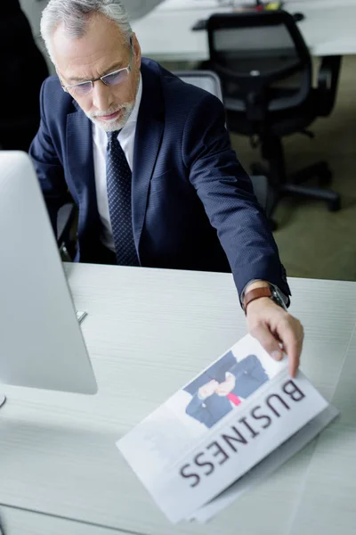 Empresario sénior tomando periódico en el lugar de trabajo en la oficina - foto de stock