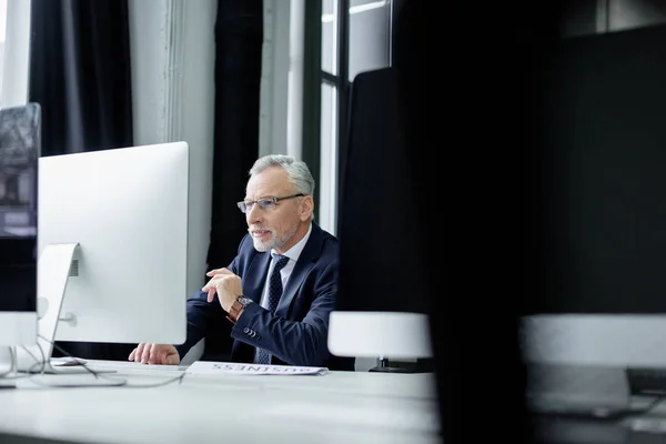 Enfoque selectivo del hombre de negocios senior que trabaja en la computadora en la oficina - foto de stock