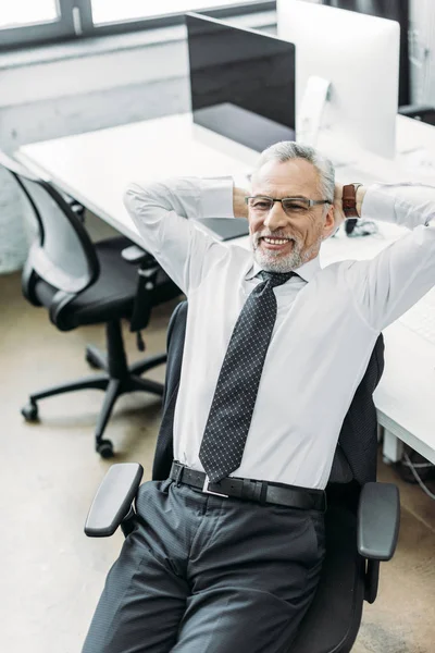 Porträt eines lächelnden Geschäftsmannes mit den Händen hinter dem Kopf im Büro — Stockfoto