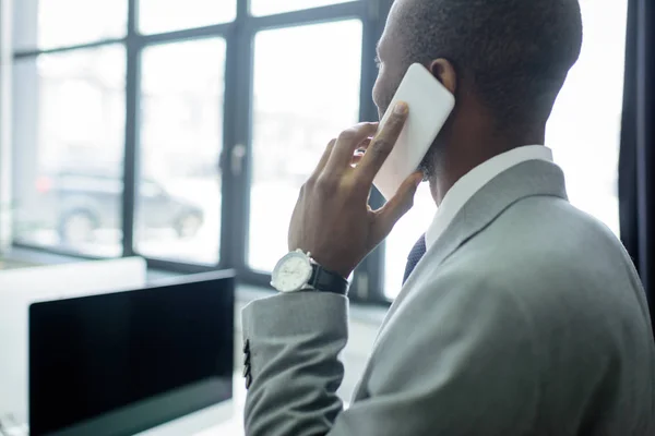 Vista parcial del hombre de negocios afroamericano hablando por teléfono inteligente - foto de stock