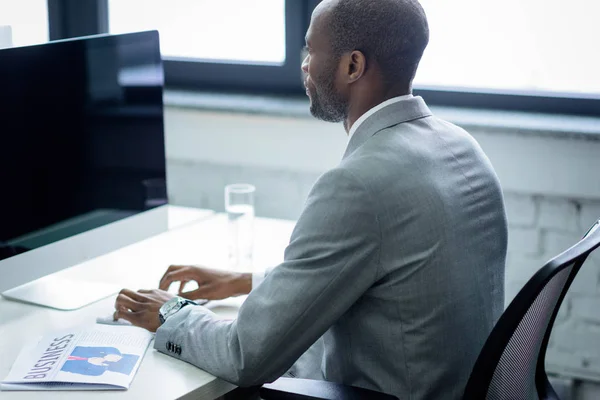 Seitenansicht eines afrikanisch-amerikanischen Mannes, der im Büro am Computer arbeitet — Stockfoto