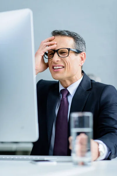 Homme d'affaires stressé regardant l'écran d'ordinateur sur le lieu de travail — Photo de stock