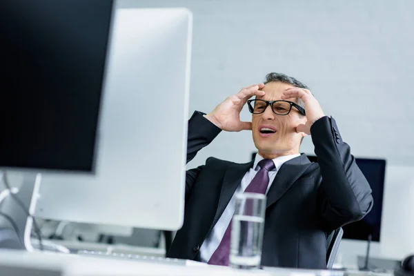 Gestresster Geschäftsmann blickt am Arbeitsplatz auf Computerbildschirm — Stockfoto