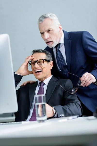 Retrato de colegas de negocios mirando juntos a la pantalla del ordenador en la oficina - foto de stock