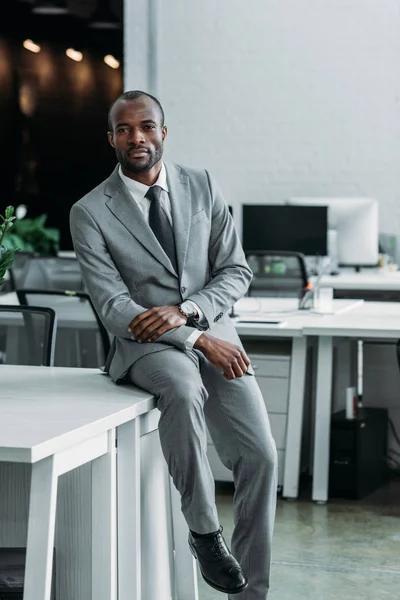 Uomo d'affari africano americano seduto sul tavolo in ufficio — Stock Photo