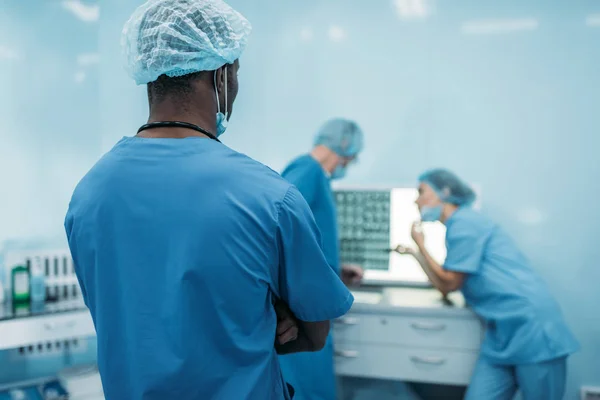Задний вид мультикультурных врачей, смотрящих на рентген пациента — стоковое фото