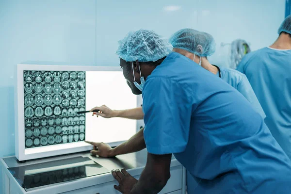 Médicos multiculturales que observan la radiografía del paciente - foto de stock