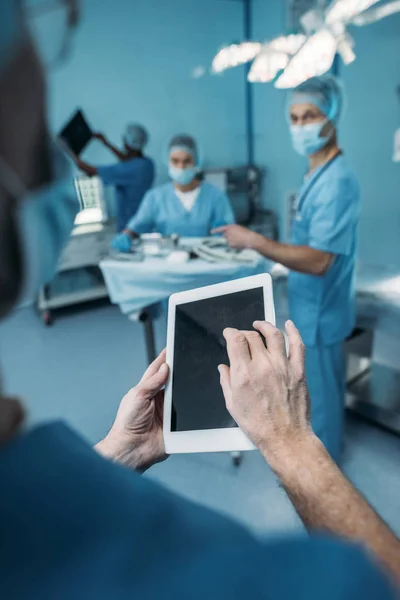 Imagem cortada do médico usando tablet na sala de cirurgia — Fotografia de Stock