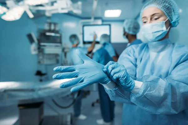 Doctor wearing medical gloves in operating room — Stock Photo