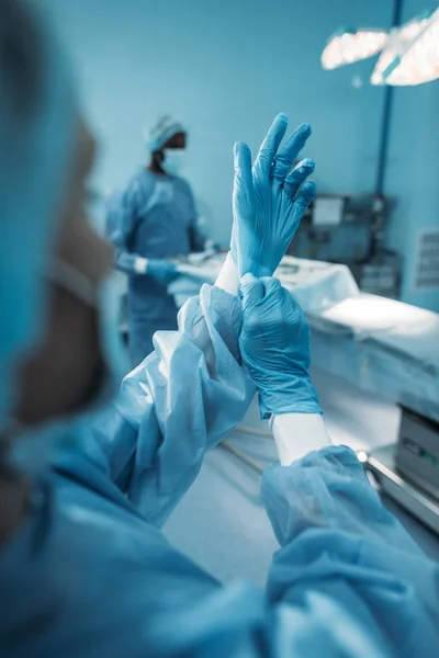 Cropped image of doctor wearing medical gloves in operating room — Stock Photo
