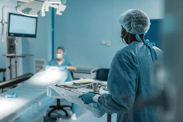 Africano americano médico segurando bandeja com ferramentas médicas para cirurgia — Fotografia de Stock