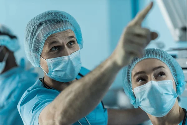 Doctor señalando algo en la sala de cirugía - foto de stock