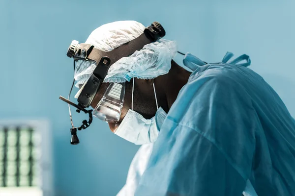 Vista lateral del cirujano afroamericano en quirófano - foto de stock