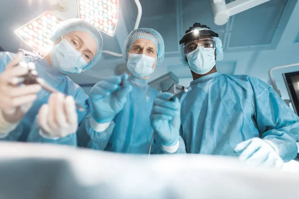 Bottom view of multicultural surgeons looking at patient during surgery — Stock Photo