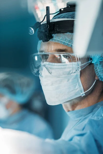 Cirujano guapo en máscara médica mirando hacia otro lado - foto de stock