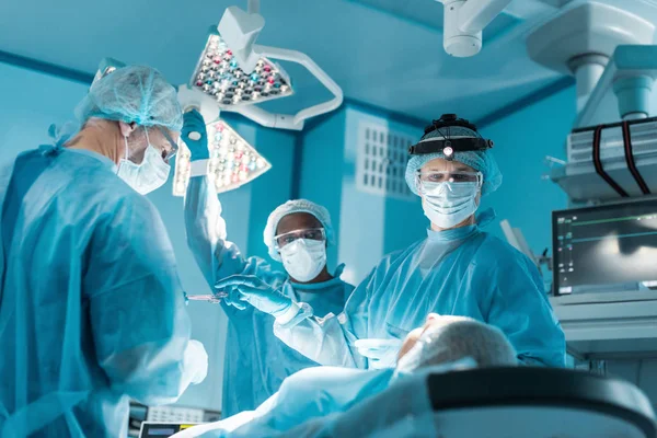 Мультикультурні хірурги та пацієнти під час операції в операційній кімнаті — стокове фото