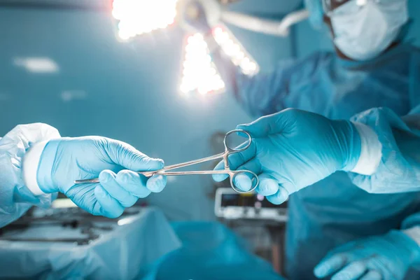 Geschnittenes Bild einer Krankenschwester, die dem Chirurgen die medizinische Schere reicht — Stockfoto
