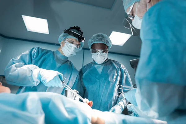 Bottom view of multicultural surgeons and patient in operating room — Stock Photo