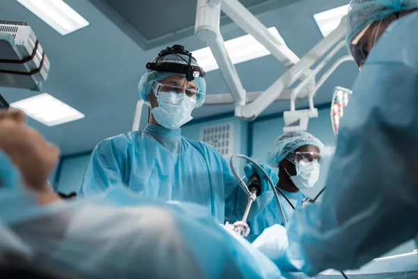 Multiethnic surgeons operating female patient — Stock Photo