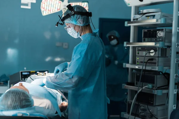 Visão lateral do cirurgião operando paciente na sala de cirurgia — Fotografia de Stock