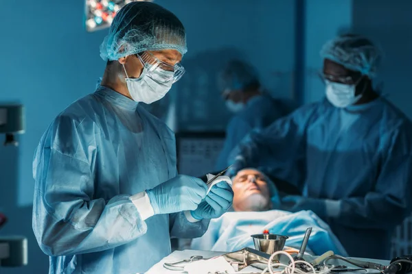 Cirurgião limpeza bisturi na sala de cirurgia — Fotografia de Stock