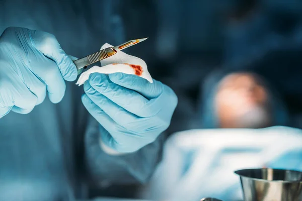 Abgeschnittenes Bild des Chirurgen, der Skalpell vom Blut reinigt — Stockfoto