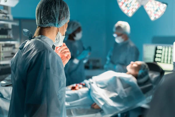 Multicultural surgeons and female patient in operating room — Stock Photo