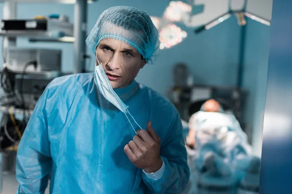 Врач снимает медицинскую маску в операционной — стоковое фото
