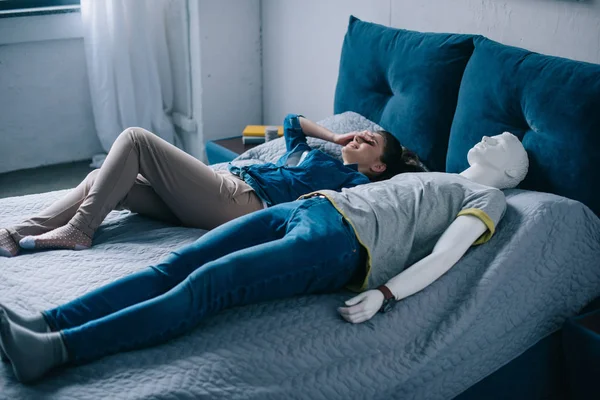 Young woman lying in bed with mannequin, perfect relationship dream concept — Stock Photo