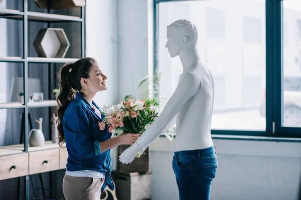 Side view of woman pretending to receive bouquet of flowers from layman doll, loneliness concept — Stock Photo