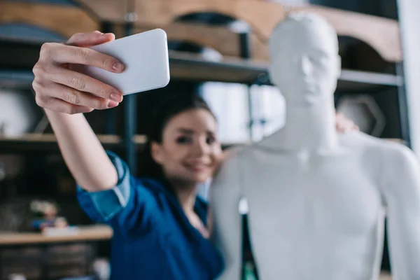 Selective focus of smiling woman taking selfie together with mannequin, perfect relationship dream concept — Stock Photo