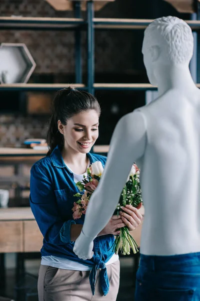Mujer joven que finge recibir flores de muñeca laica, concepto de sueño de relación perfecta - foto de stock