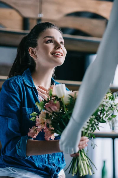 Mujer joven que finge recibir flores de muñeca laica, concepto de sueño de relación perfecta - foto de stock