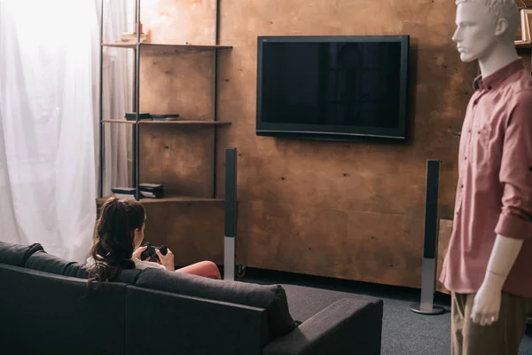 Back view of woman playing vídeo game and mannikin aside at home, one way love concept — Fotografia de Stock